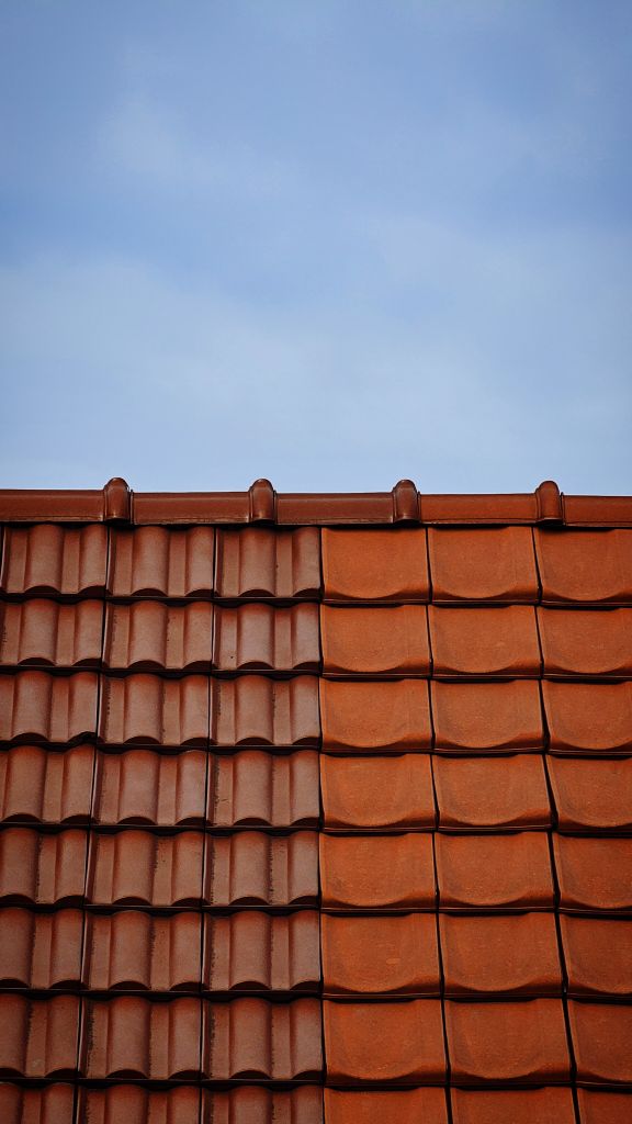 Close-up view of a tiled roof contrasting with a clear blue sky.